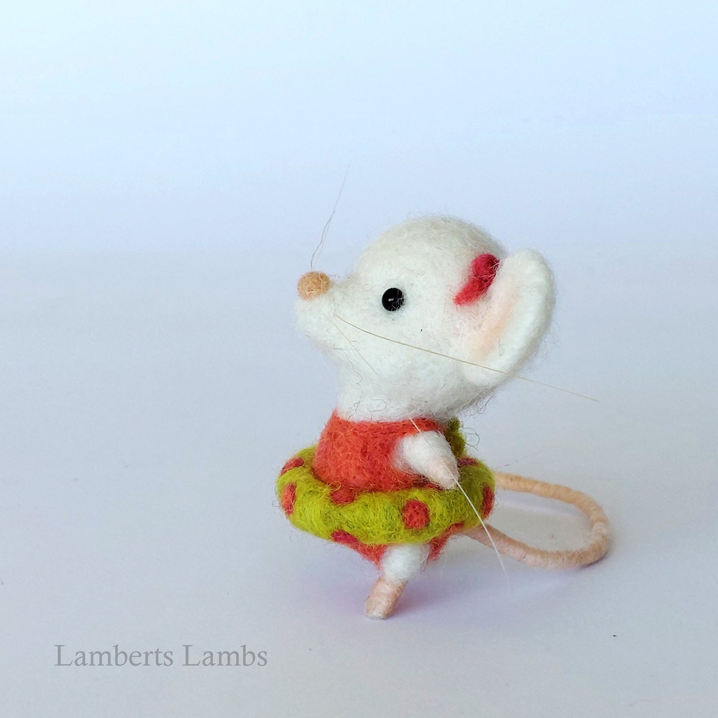 White needle felted mouse in an orange swimsuit with an inflatable ring.