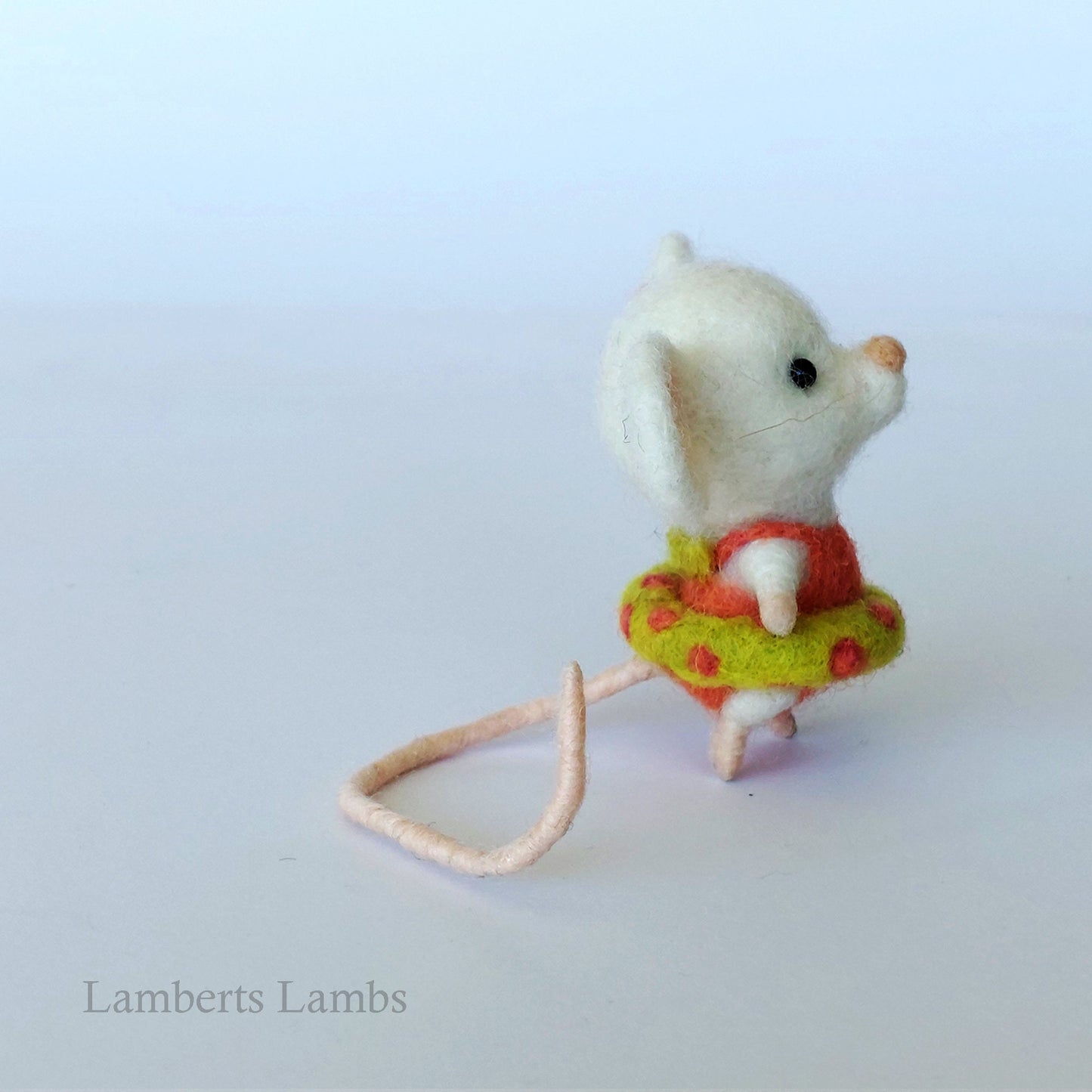 White needle felted mouse in an orange swimsuit with an inflatable ring.